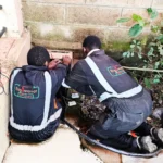 Power project. Technicians installing new power cable to main cutouts outside a building block.