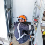 Power project. Technician installing an electrical bypass panel for the new AVR supplied.