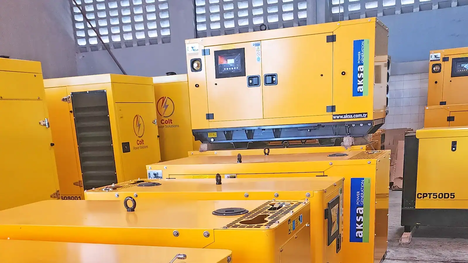 AKSA diesel generators in warehouse storage ready for supply and deployment for backup power systems.