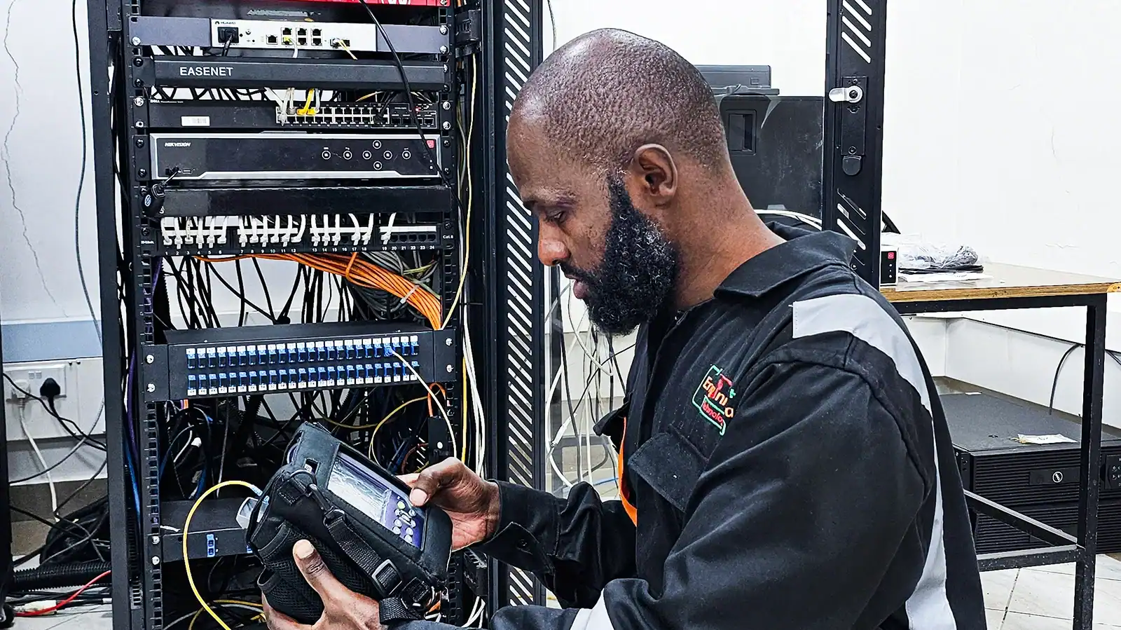 Technician configuring enterprise network infrastructure and structured cabling in a server rack.
