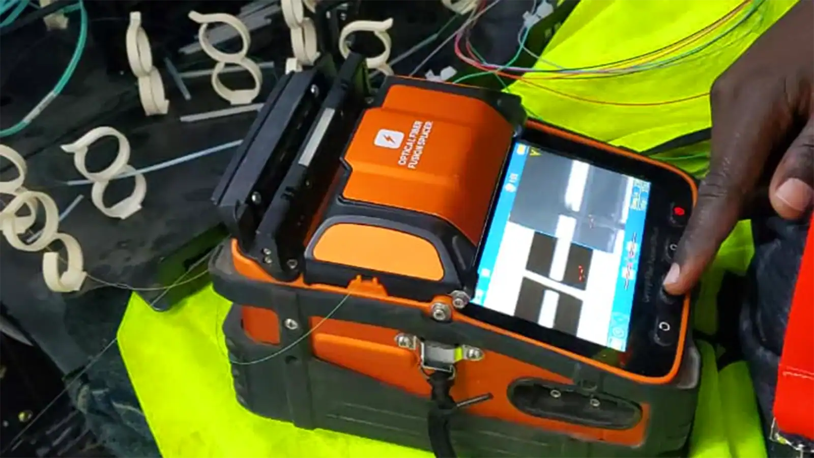Technician performing fibre optic fusion splicing and termination using precision splicing equipment.