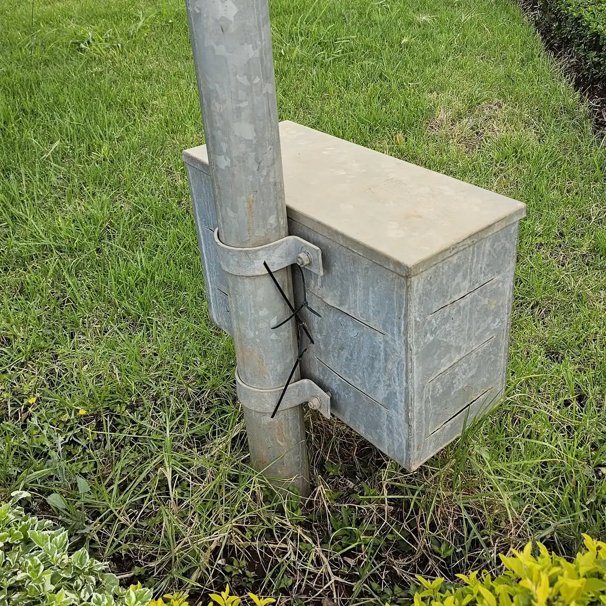 Pole-mounted battery and control enclosure for integrated solar lighting system installation.