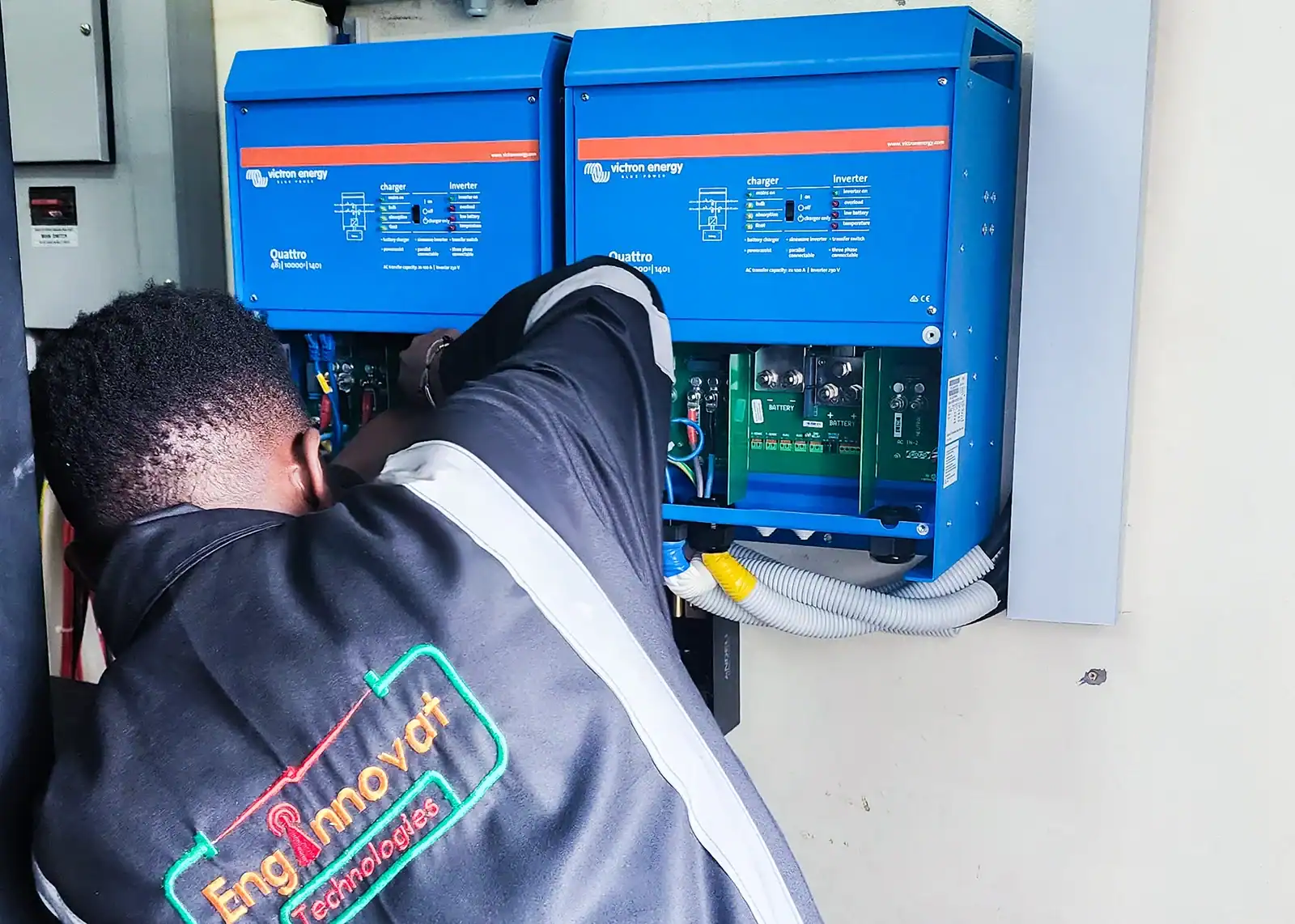 Technician installing Victron Quattro inverter and battery system for UPS backup in a server room.
