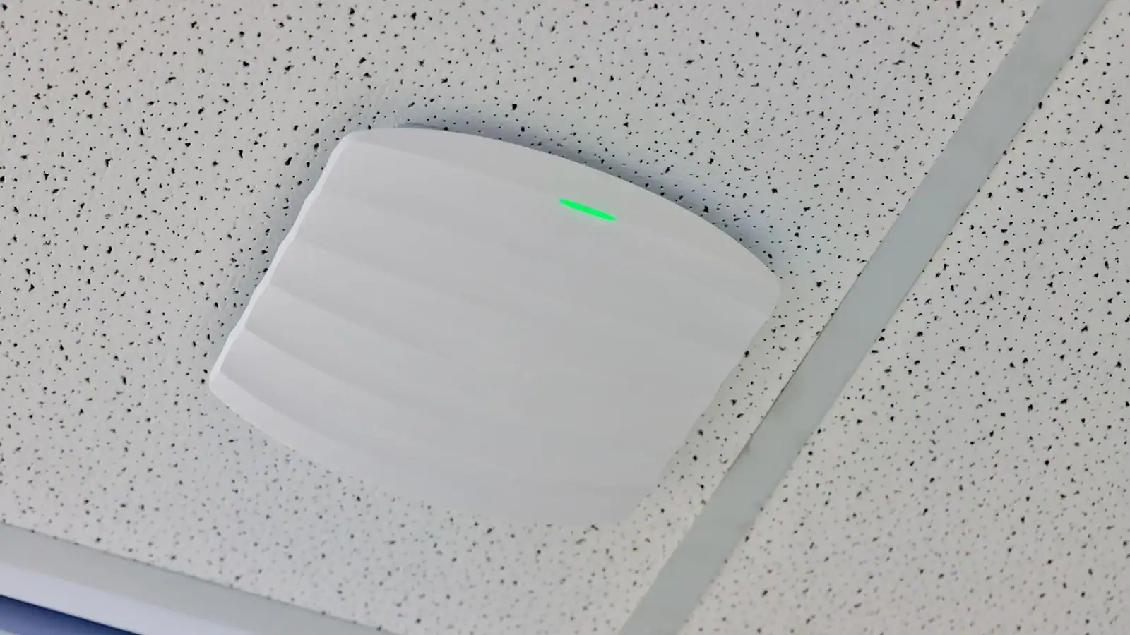 Ceiling-mounted wireless LAN access point providing office WiFi connectivity and network coverage.