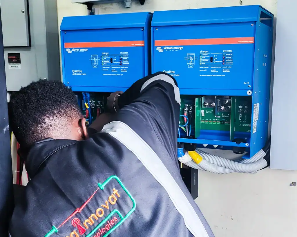 Enginnovat technician installing 20 kVA Victron Quattro inverter and Weco lithium battery backup in a server room.