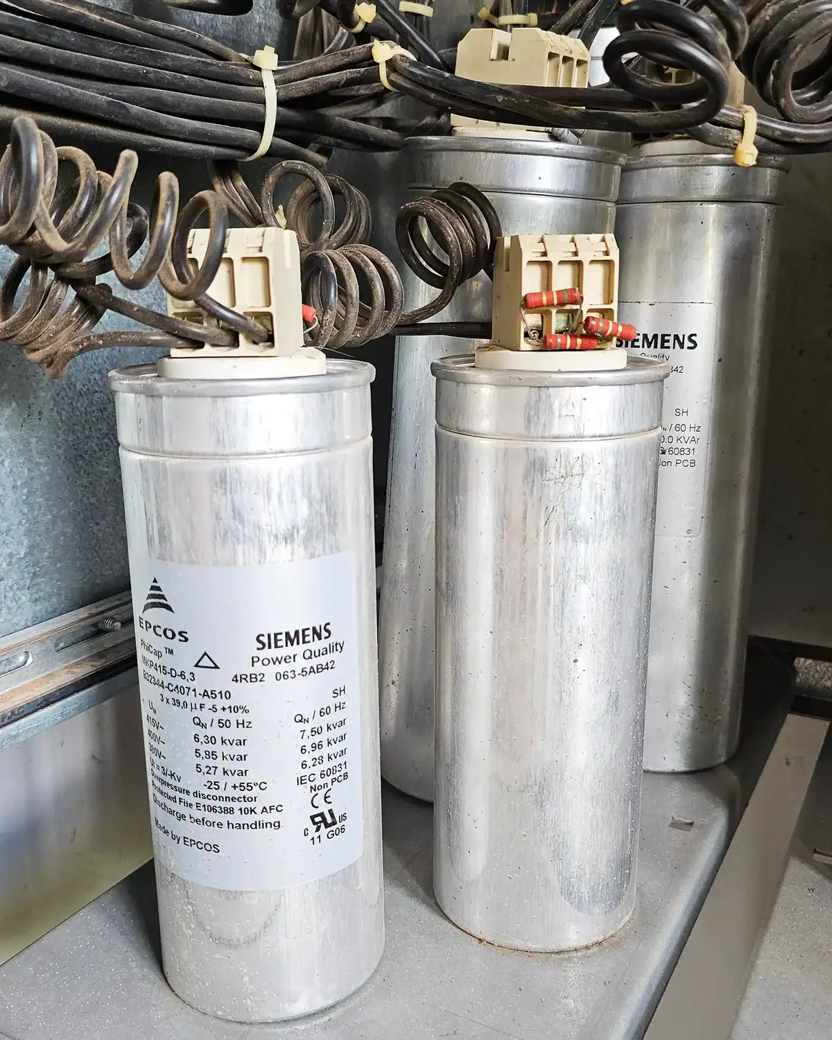 100kVAR power factor correction capacitor bank installed in a three-phase main power switchboard for electrical system regulation in an institutional facility.